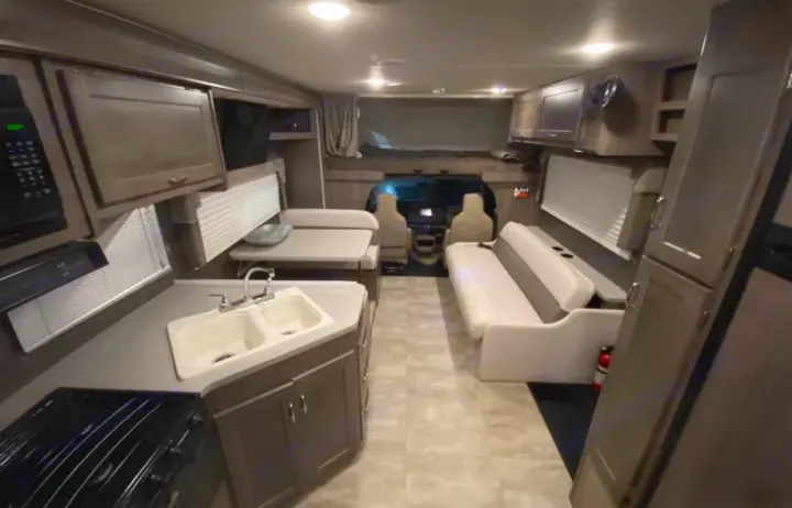 Spacious RV rental interior with kitchen, dining, and living areas. Features an overhead bunk and modern amenities.. Winnebago Winnebago Spirit 2017