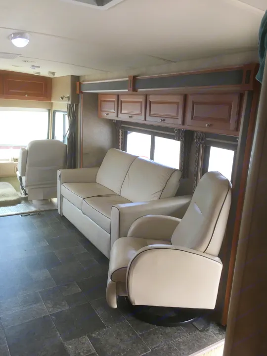 Comfortable RV rental living area with cream leather couch, recliner, and durable tiled floor. Ready for your next adventure.. Winnebago Itasca Sunova 2014