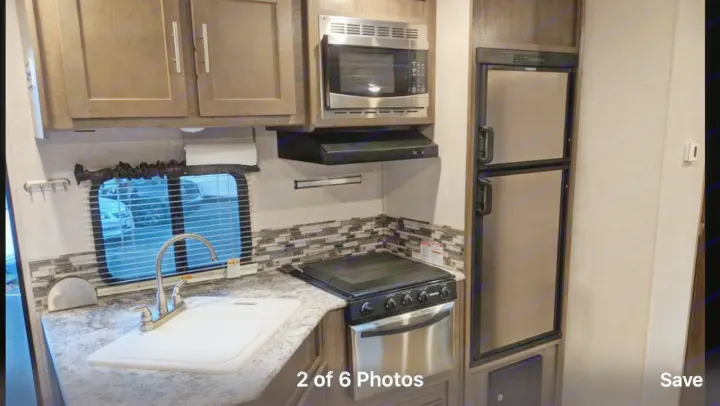 Compact RV rental kitchen with sink, microwave, stove, fridge, and cabinets. Ideal for your next adventure.. Forest River Surveyor bunkhouse 2018