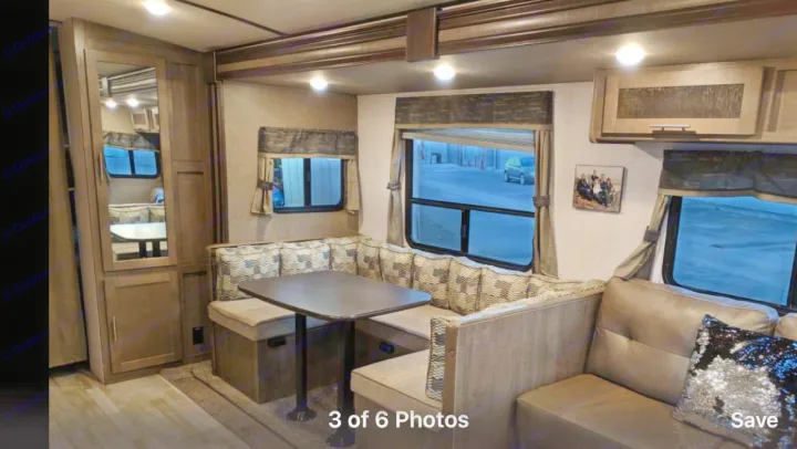 Cozy RV rental interior with a patterned U-shaped dinette, brown couch with sequin pillow, and multiple windows. Ideal travel space.. Forest River Surveyor bunkhouse 2018