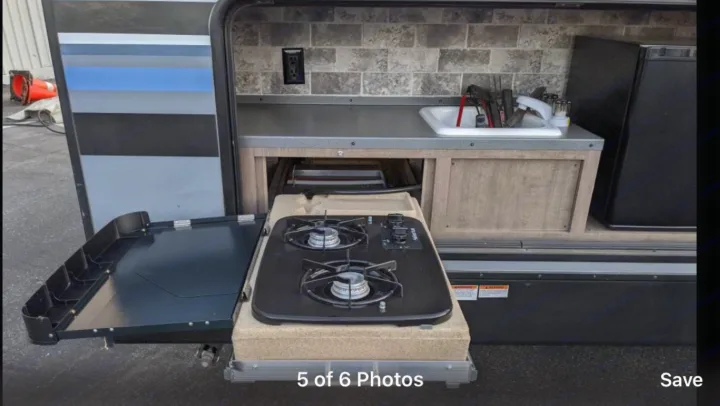 Outdoor kitchen in an RV rental: pull-out gas stove, sink, fridge, and prep counter for easy camping meals.. Forest River Surveyor bunkhouse 2018
