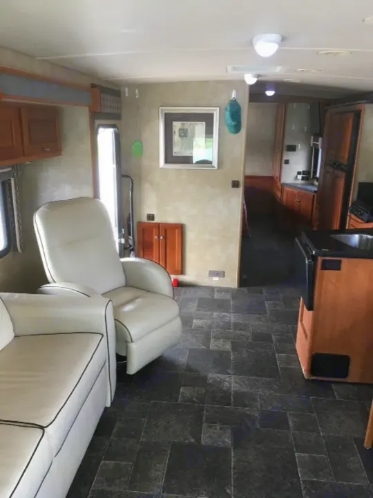 Comfort meets style in this RV rental's living area, featuring white seating, wood accents, and sleek tile floor.. Winnebago Itasca Sunova 2014