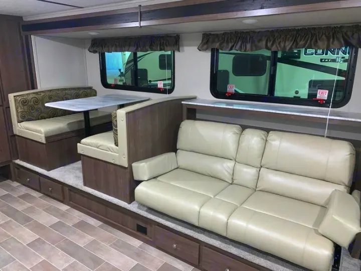 Spacious RV rental slide-out: Dinette booth, table & long sofa create a comfy living area for travelers.. Keystone Hideout 2019