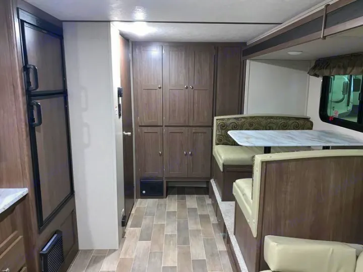 RV rental interior with a fridge, dining booth, and ample wood-look cabinets. A cozy, functional travel space.. Keystone Hideout 2019