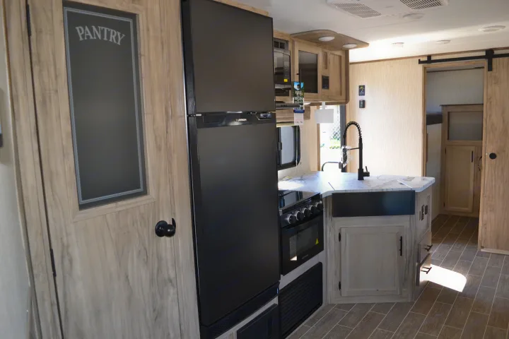 Modern RV rental interior featuring a full kitchen with pantry, appliances, and a sliding barn door leading to living space.. Forest River Other 2020
