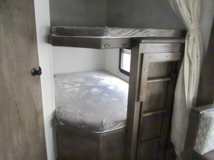 View of a compact **rv rental** interior, featuring two bunk beds, a ladder, and a window for sleeping.. Forest River Evo 2021