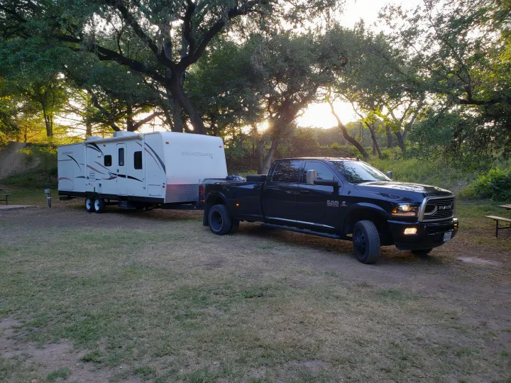 A black Ram 3500 truck and Sportsmen travel trailer parked at a sunny campsite, ready for your RV rental adventure.. Other Other 2013