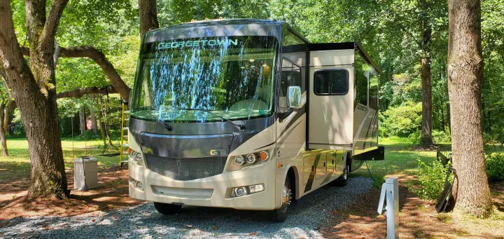 A large Georgetown GT5 RV rental, ready for adventure, is parked at a shaded forest campsite.. Forest River Georgetown 2020
