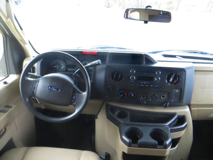 Interior view of an RV rental: Ford dashboard features a steering wheel, radio, climate controls, and cup holders, ready for travel.. Thor Majestic 2015
