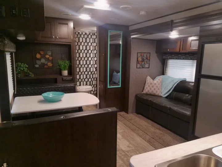 Cozy RV rental interior showing a dining booth, living area with couch, and part of the kitchen. Modern and comfortable design.. Heartland Pioneer 2019