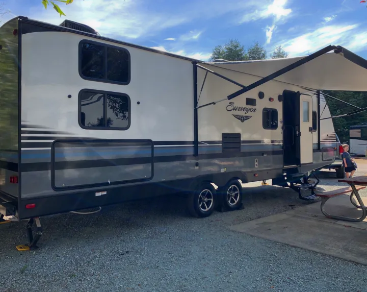 This bright 'Surveyor' RV rental is set up on a gravel site with an extended awning, perfect for camping.. Forest River Surveyor bunkhouse 2018