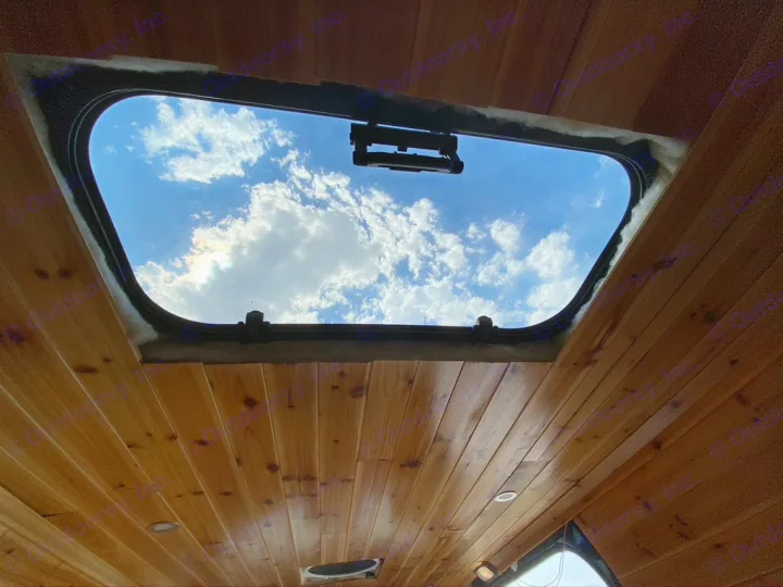 RV rental interior: A wooden ceiling features a large skylight showing a bright blue sky with white clouds.. Mercedes-benz 4x4 Sprinter mwb 2019