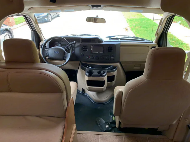 RV rental interior: Looking forward at the spacious cockpit with dashboard, Ford steering wheel, and front seats.. Thor Chateau 2019