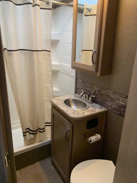 This RV rental bathroom features a compact shower, vanity sink, medicine cabinet, and toilet for comfortable travel.. Thor Chateau 2019