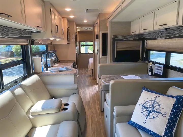 Spacious RV rental interior: modern kitchen, dining & living area with recliners.. Thor A.C.E 2020