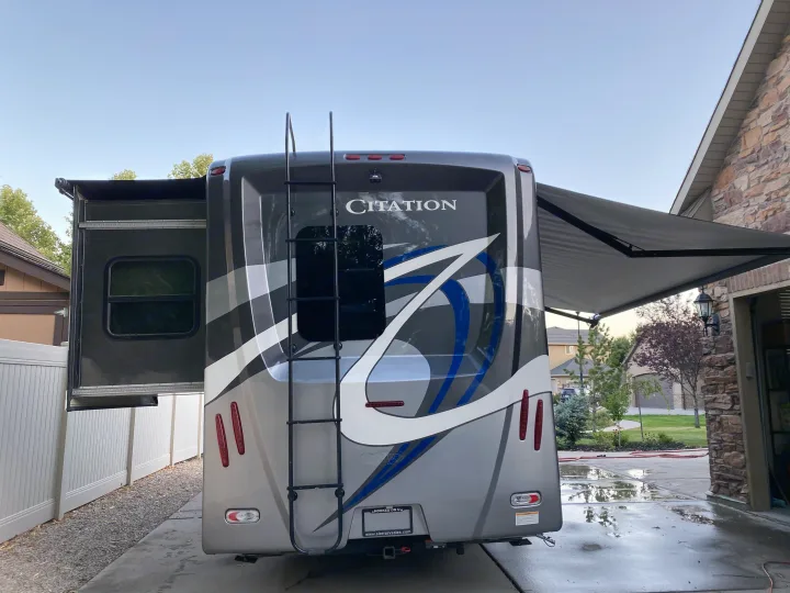 Grey Citation motorhome, slide-out and awning extended, parked on a driveway. Perfect for an RV rental adventure!. Thor Motor Coach Citation 2018