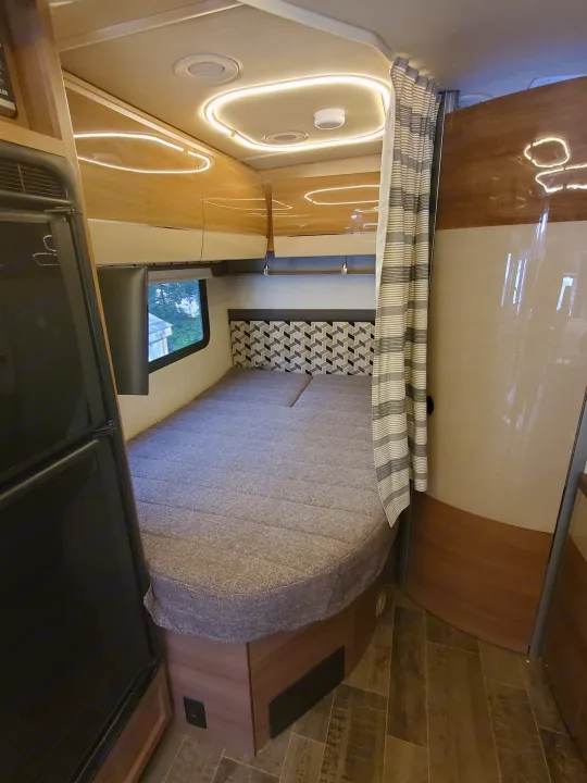 Cozy RV rental interior featuring a comfortable bed, window, and stylish modern lighting. Ideal for your next journey.. Winnebago View 24j 2018