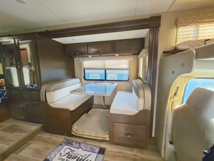 Inside a comfy RV rental: a bright dinette area with built-in benches, table, and cabinets, perfect for travelers.. Thor Freedom Elite 2019