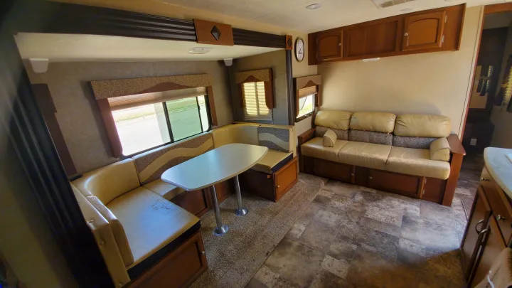 Comfortable RV rental interior featuring a dinette, sofa, and ample storage, ideal for road trips.. Coachmen Freedom Express 2015