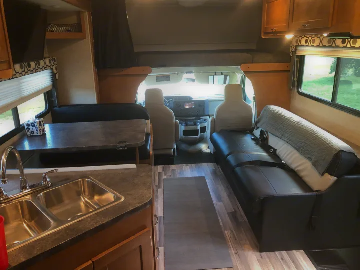 Full view of a modern RV rental interior featuring kitchen, dinette, sofa, bunk, and driver's cab.. Winnebago Minnie Winnie 2017