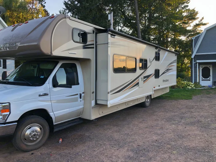 Clean Winnebago Class C RV, great for an rv rental, parked on a dirt driveway beside a house.. Winnebago Minnie Winnie 2017