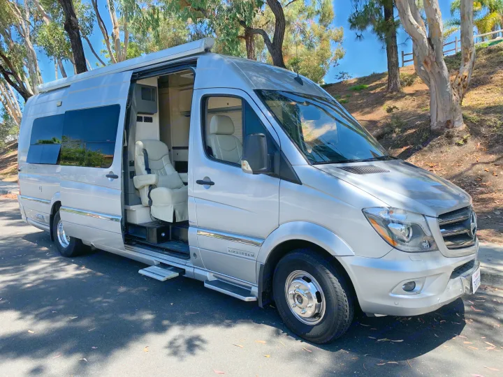 Spacious silver Airstream camper van. Ideal rv rental for comfortable travel with an open side door showing the luxurious interior.. Airstream Airstream 2014