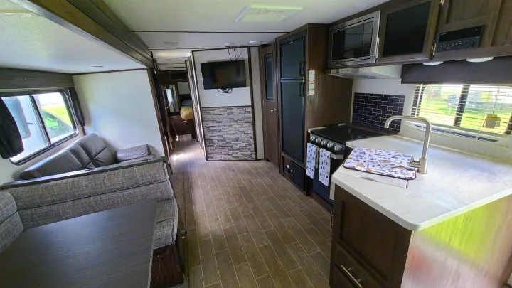 Modern RV rental interior with a fully equipped kitchen, dining area, comfortable living space, and a hallway to the bedroom.. Forest River Alpha Wolf 2020