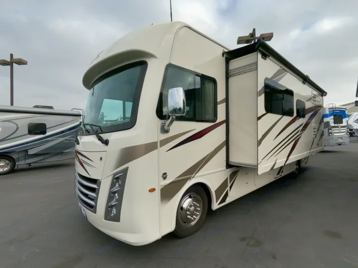 This cream Class A RV rental, with an extended side slide-out, is parked on asphalt, ready for spacious road trip adventures.. Thor Motor Coach A.C.E 2020