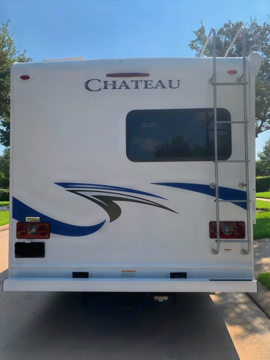 Rear view of a white Chateau RV rental, featuring a ladder, window, and tail lights, ready for travel adventures.. Thor Chateau 2019