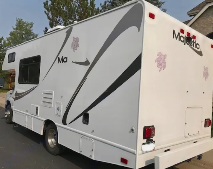 White Class C RV rental, Majestic branded, with distinctive black/grey graphics & turtle decals. Parked outdoors.. Thor Motor Coach Four Winds Majestic 2014