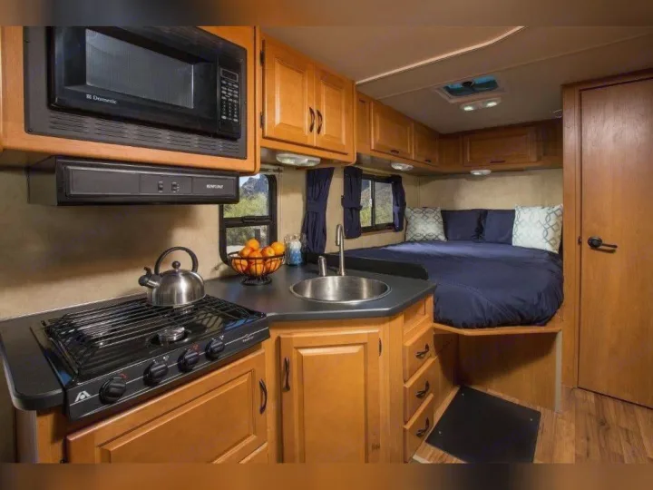 Well-equipped RV rental: kitchen with microwave, stove & sink, plus a comfy bed. Ideal for mobile living.. Thor Motor Coach Four Winds Majestic 2014