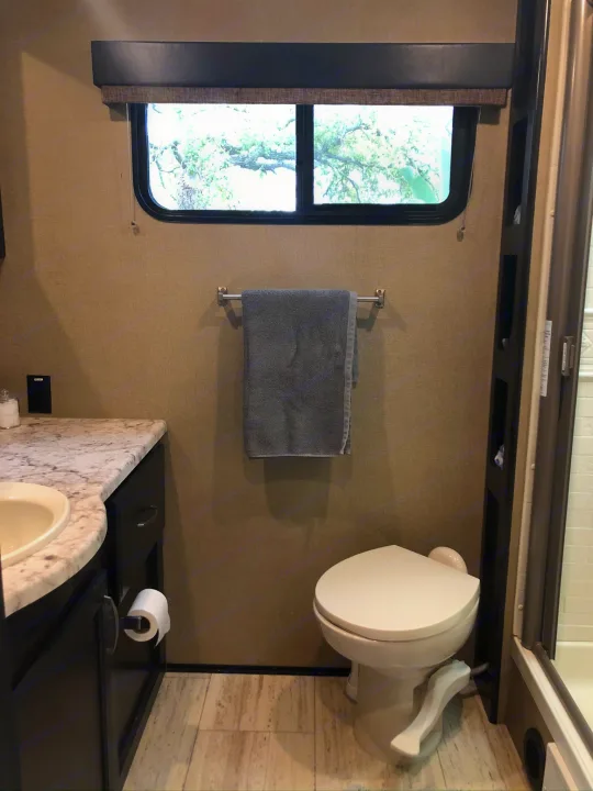 RV rental bathroom interior with a toilet, sink vanity, towel rack, and shower. Compact and functional design.. Grand Design 2600RB 2018