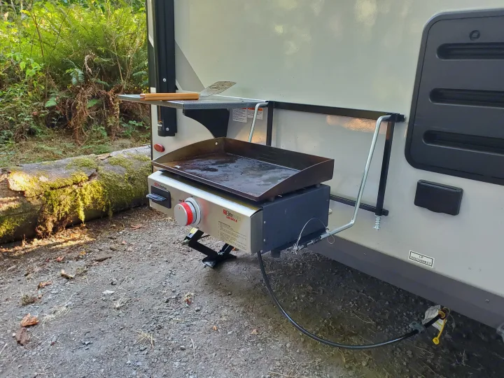 An RV rental is equipped for outdoor cooking with a Suburban Elite Series griddle attached, connected to propane.. Forest River Rockwood Geo Pro 2021