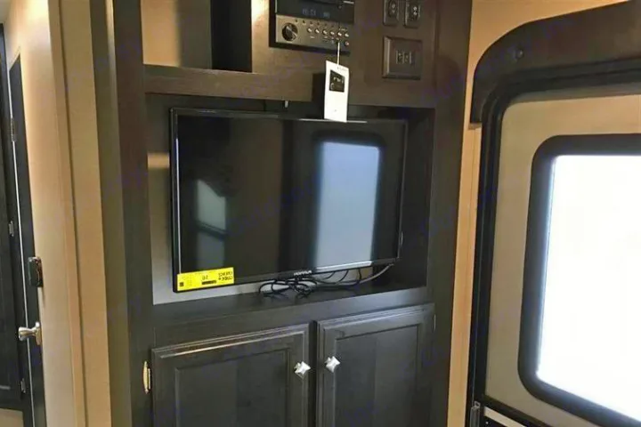 Inside this RV rental, a dark wood entertainment center includes a mounted TV, stereo system, and storage cabinets, providing comfort.. Venture Rv Sonic Lite SL 169VRD 2018