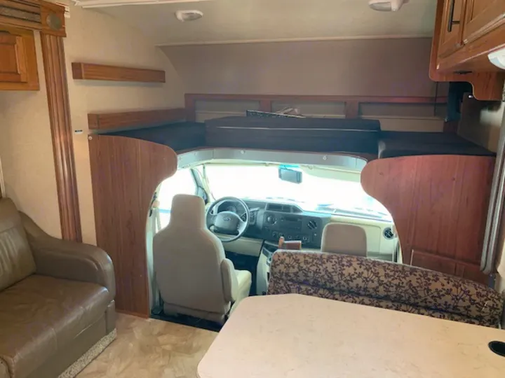 This rv rental interior highlights the cockpit, over-cab sleeping bunk, sofa, and dinette.. Jayco Redhawk 31X 2017