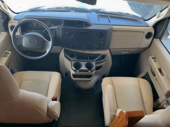 RV rental: Inside a Ford motorhome cab, showing the dashboard, steering wheel, and two tan front seats. Simple and functional interior.. Jayco Redhawk 31X 2017