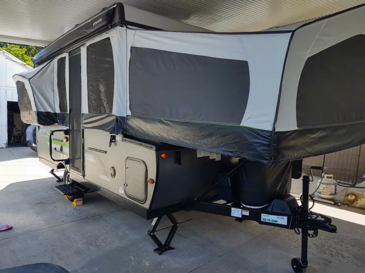 Grey/black Rockwood pop-up camper, an RV rental, fully set up under a carport with Dometic awning.. Forest River Rockwood Freedom 2021