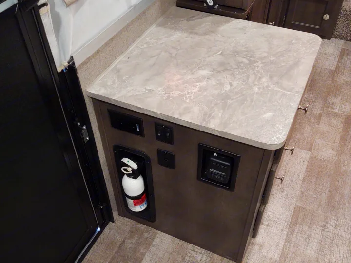 RV rental interior side panel: fire extinguisher, Suburban thermostat, and power outlets. Essential controls and safety.. Forest River Rockwood Freedom 2021