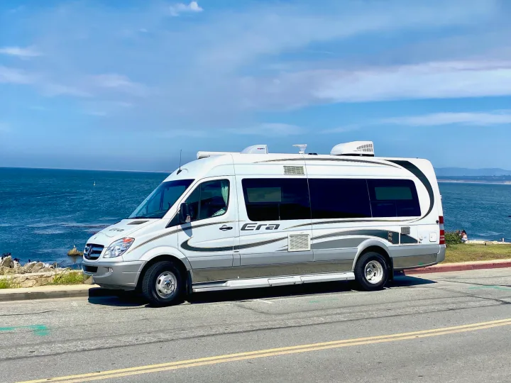 Sleek white Era rv rental parked on a sunny day, showcasing a stunning ocean view along the coastline.. Other Other 2013