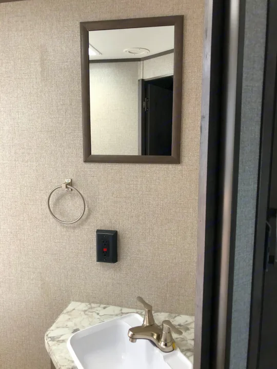 Inside an RV rental bathroom, featuring a mirror, towel ring, sink with faucet, and GFCI outlet on textured walls.. Jayco Jay Flight 2021