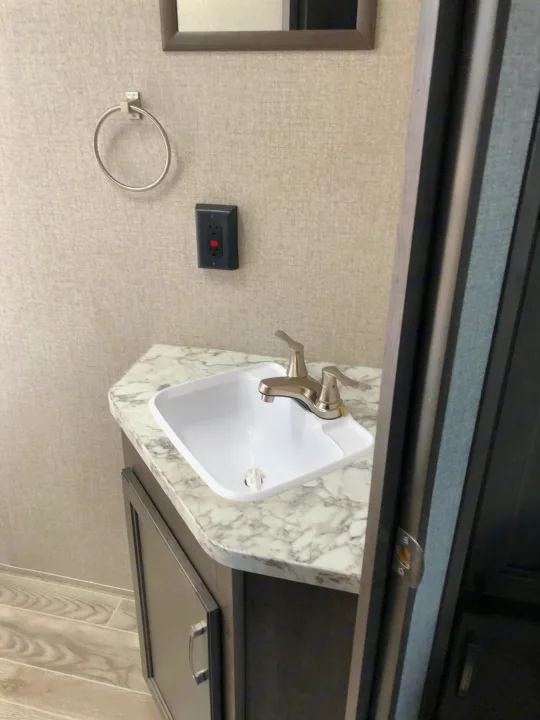 Experience comfort in your RV rental with this compact bathroom vanity, featuring a white sink, modern faucet, and marbled counter.. Jayco Jay Flight 2021