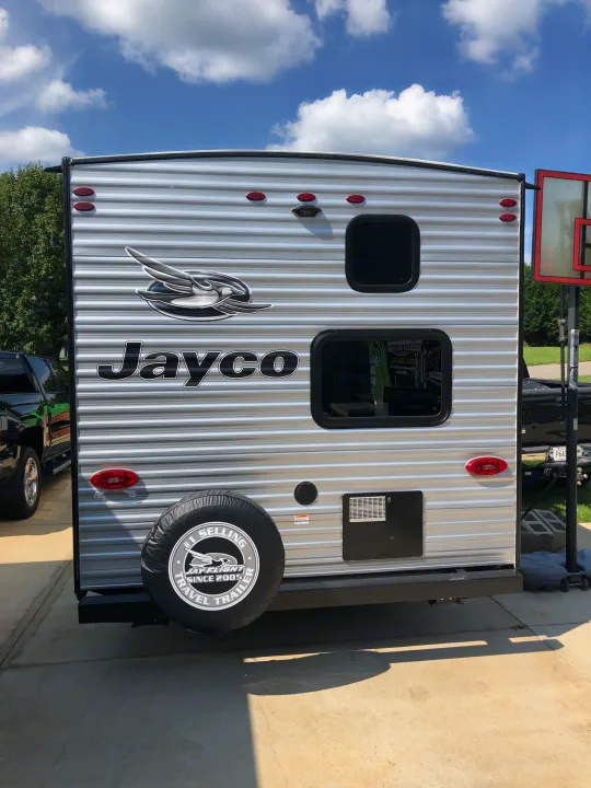Ready for your RV rental adventure! Rear view of a silver Jayco travel trailer with a spare tire, windows & lights.. Jayco Jay Flight 2021