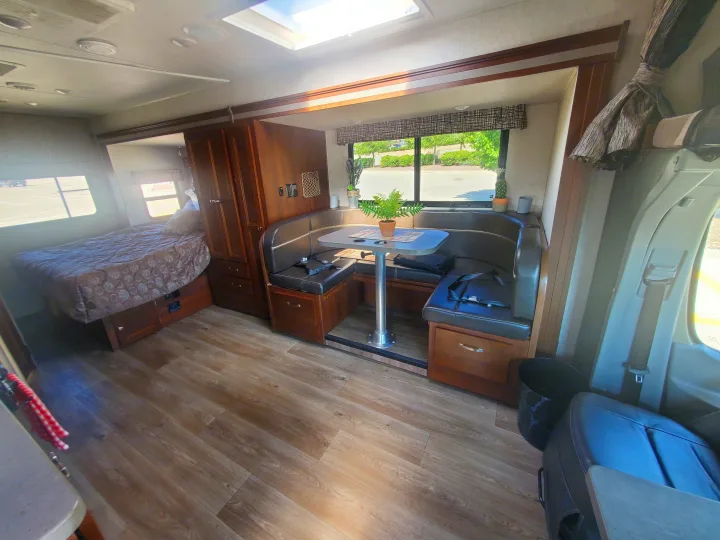 RV rental interior: features a comfy bed, U-shaped dinette, wood floors, and a skylight. Your home on wheels awaits!. Forest River Sunseeker 2018