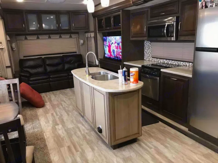 Explore this spacious RV rental interior! Features a full kitchen with island, living area with large TV & sofa. Comfort on the road.. Grand Design Solitude 2016