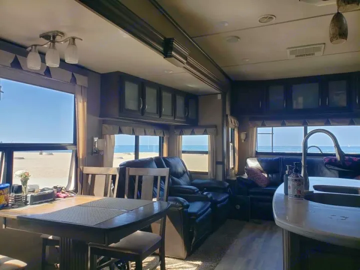 Enjoy an RV rental with a stunning beachfront view. This spacious interior includes a dining area & comfy seating.. Grand Design Solitude 2016