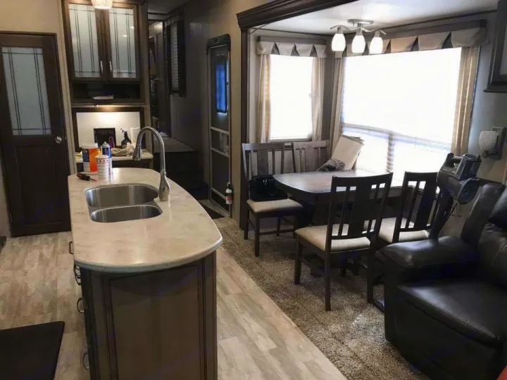 Explore this spacious RV rental interior: modern kitchen, dining area with bright windows, and living space.. Grand Design Solitude 2016