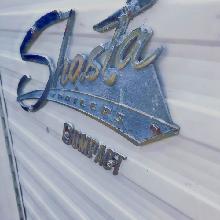Vintage "Shasta Trailers COMPACT" emblem on an RV. A classic option for your next unique RV rental adventure!. Shasta Compact 1971