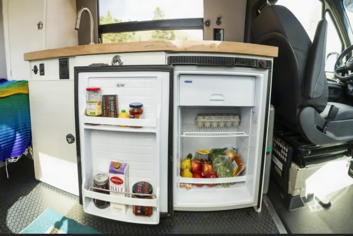 Inside this RV rental, a compact, well-stocked refrigerator and kitchenette are ready for travel.. Mercedes-Benz Sprinter 2020