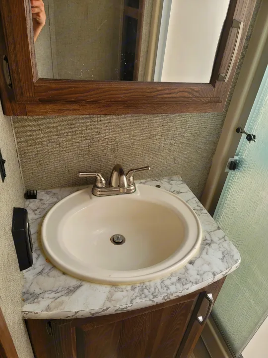 RV rental bathroom vanity with sink, faucet, & mirror cabinet. Features textured walls & overhead shower glass.. Keystone RV Cougar 2018