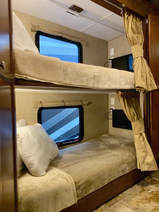 Comfortable RV rental bunk beds with windows, TVs, and privacy curtains, ideal for family travel.. Coachmen Mirada 2016